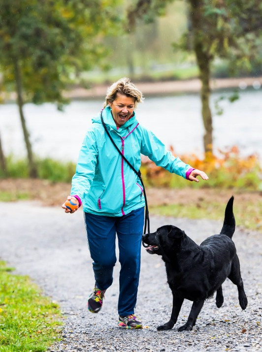 Frau spaziert und spiel mit ihrem Hund