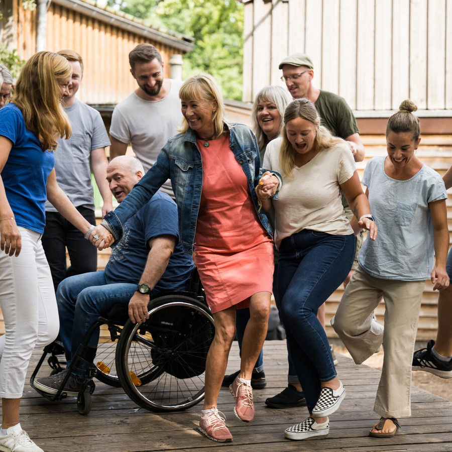 Gruppe Menschen stehen auf einem großen Balancebrett und haben spaß