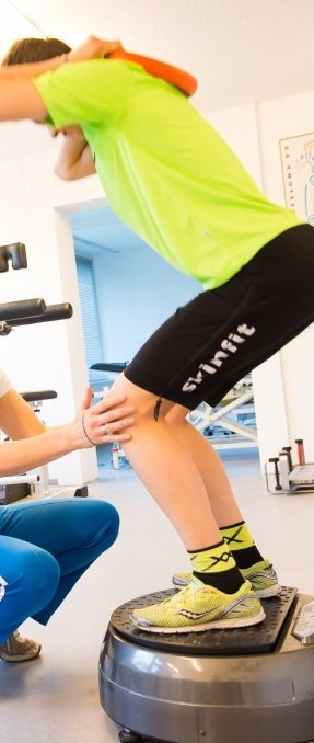 Person steht auf Balancegerät und wird angeleitet