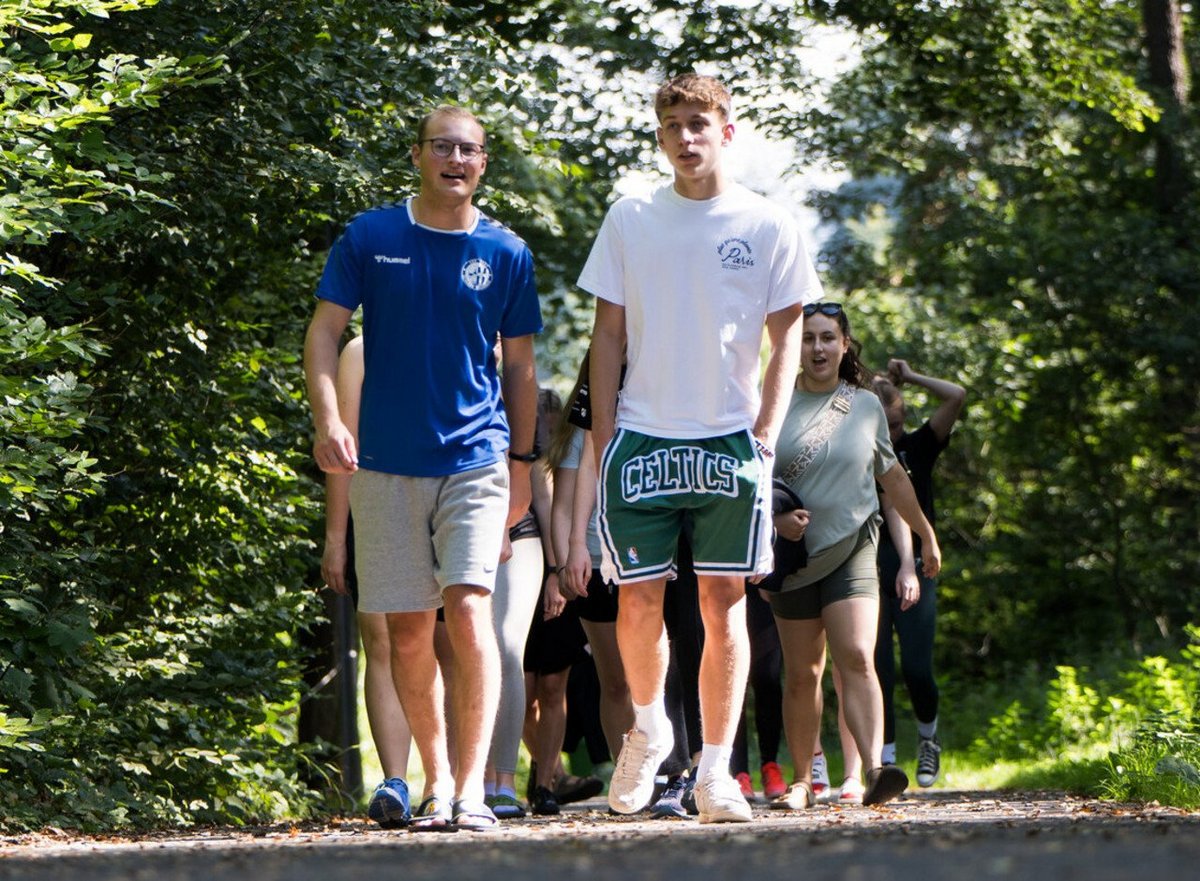 Gruppe junger Menschen spaziert im Wald